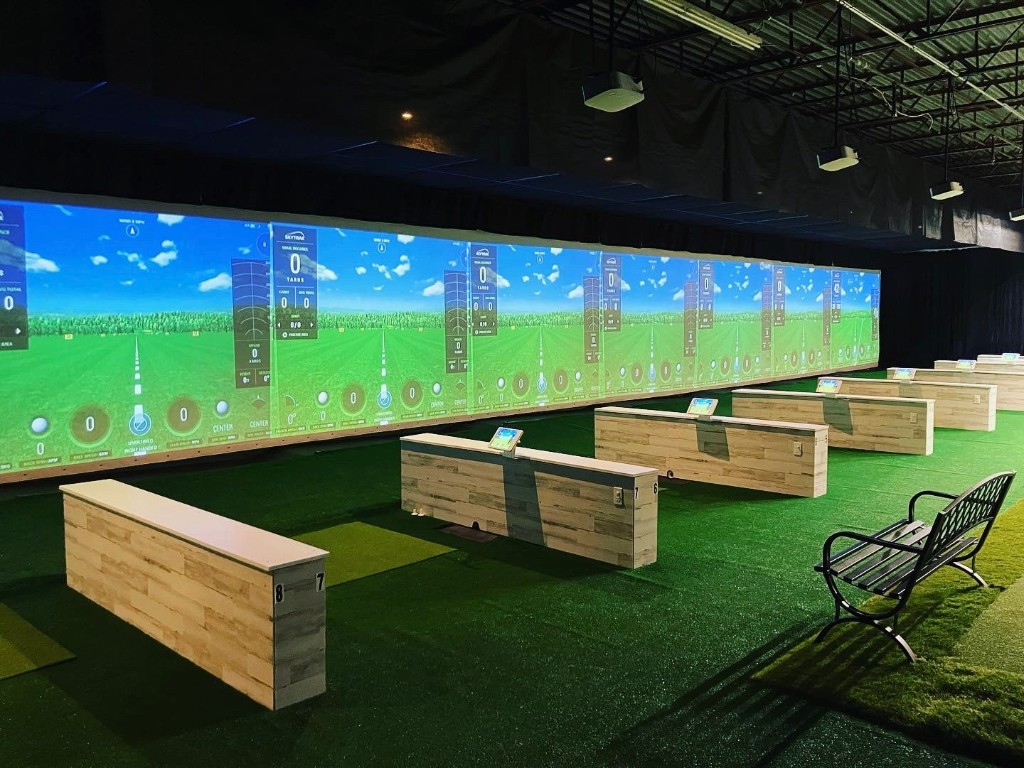 Tee24 indoor golf facility with simulator bays and driving range screens